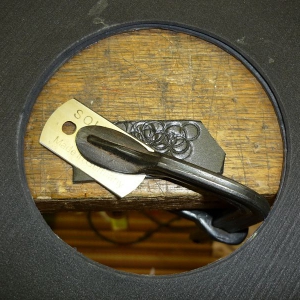 Radkappe-7. 
Um die Kontur an die Bremstrommel anzupassen, ist hier eine Herdplatten-Schabeklinge über eine Beilage am Tisch festgespannt. Durch Drehen der Radkappe kann man einen parallelen Einschnitt in der Bohrung erzeugen. Das zu entfernende Stück wi