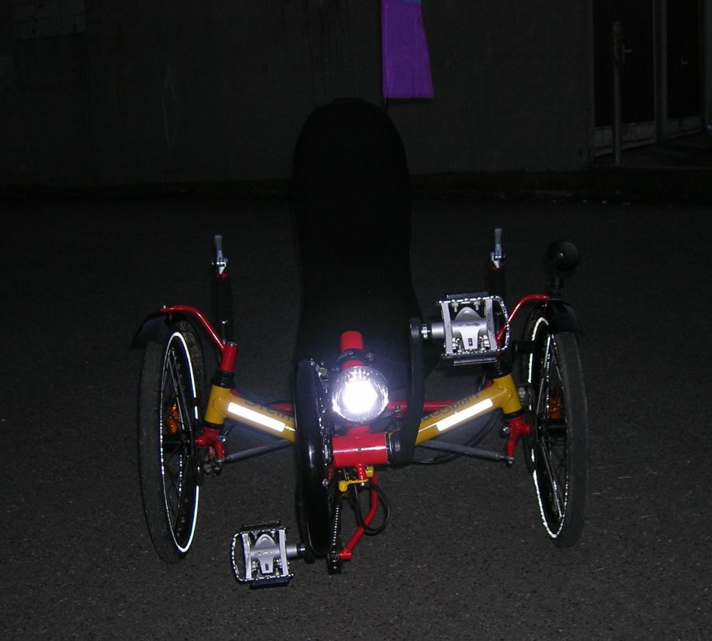 Trike von vorne, die 3M-Reflex-Folie am vorderen Träger ist ein Sicherheitsplus; man sieht die neue Kettenradabdeckung von HP ("Rammschutz" vulgo "Fußgängerfräse"); die Kombi-Pedale sind von Shimano PD-M324 (MountainBIKE 07/08 Urteil: Sehr Gut! Universalp