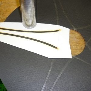 Radkappe-4. 
Mittels einer Schablone, bei mir 0,5 mm Kunststoff, wird die Kontur mittels orangem dünnen wasserfestem Faserschreiber auf dem Zuschnitt angezeichnet. Anschließend die Klebestellen für das Deco mit Pattex als Haftgrund bestrichen.
