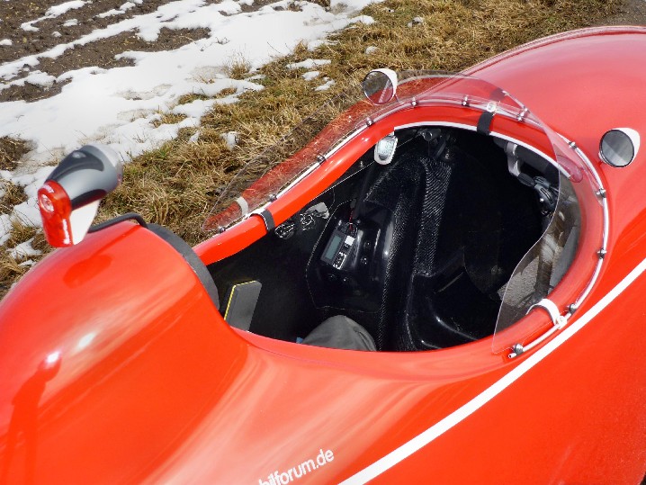 Einstiegöffnung mit Windschild. 
Hinter dem Schild ist es windstill. Nur Luftwirbel, die sich am Ende ablösen, spürt man im Nacken. Das WSchild ist allerdings sehr kratzempfindlich. Man sieht alle Polier- und Reinigungsschlieren. Nachteilig ist auch, daß