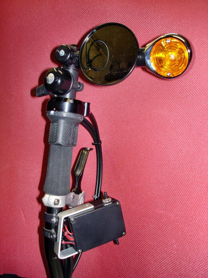Ochsenaugenblinker rechts mit Spiegel, Glocke und Blinkerschalter.
Der Blinkerschalter dient gleichzeitig als Handauflage, so wie links der Handbremshebel